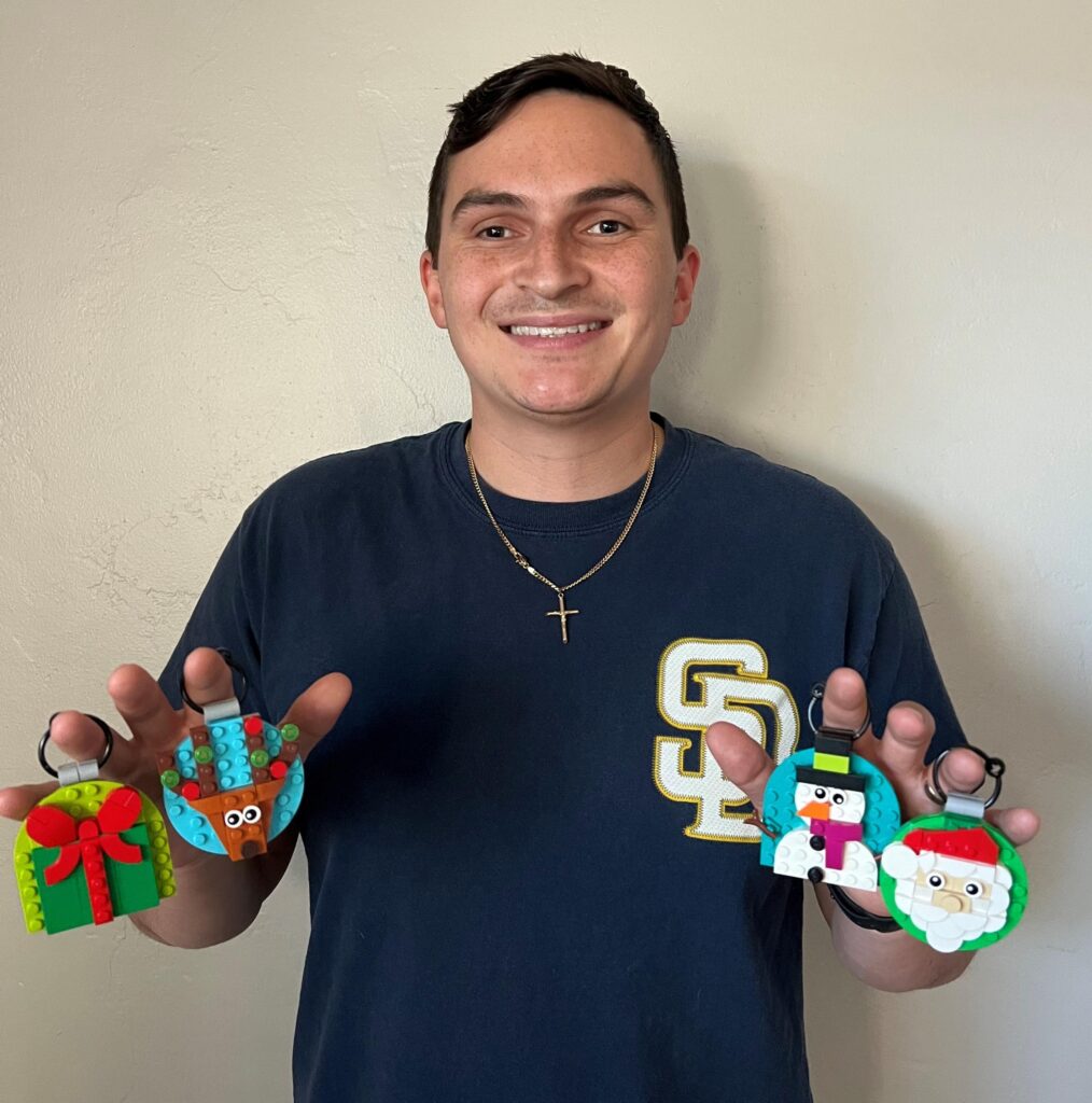 Photo of Daniel with a big smile holding the Christmas Ornaments build.