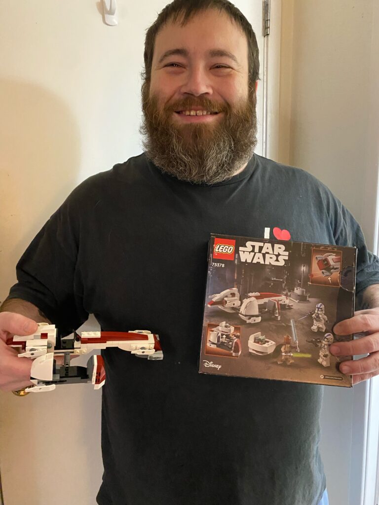 Jacques holding a LEGO set and the box it came in with a big smile on his face!